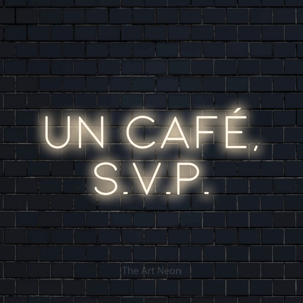 “Un café, s.v.p.” LED neon sign in warm white, with thin, widely spaced lettering across 2 lines, shown against a dark navy brick wall.