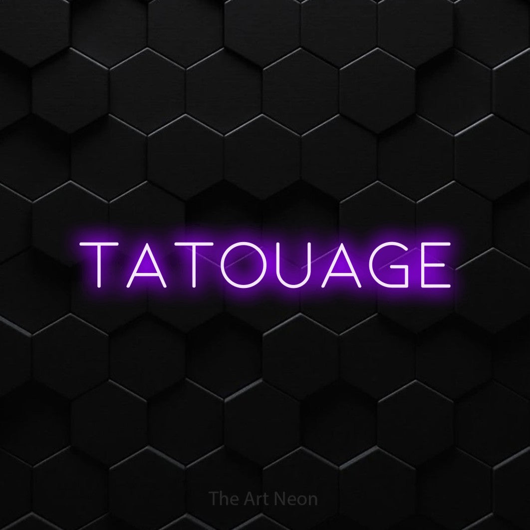 “Tatouage” LED neon sign in purple, with thin, widely spaced lettering, shown against black hexagonal wall tiles.