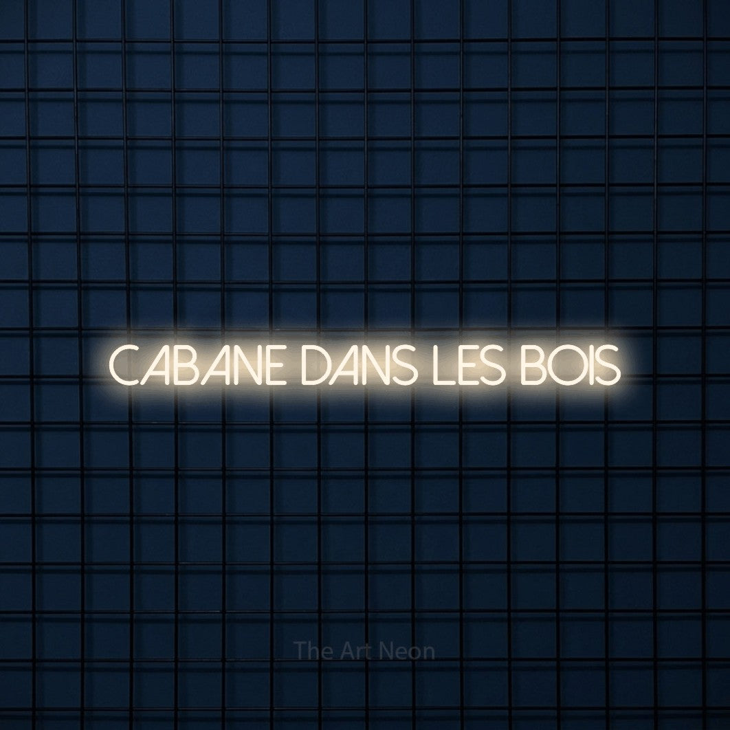 “Cabane dans les bois” LED neon sign in warm white, with thin sans-serif lettering, shown against a dark blue grid.