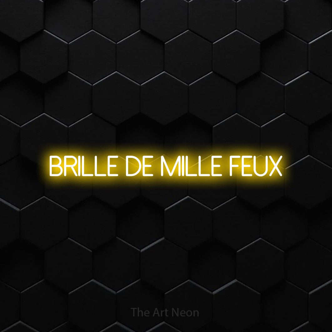 “Brille de mille feux” LED neon sign in yellow, with thin sans-serif lettering, shown against black hexagonal wall tiles.