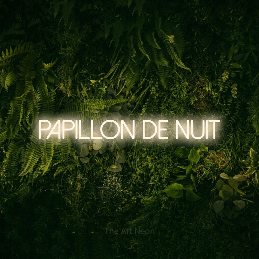 “Papillon de nuit” LED neon sign in warm white, with thin sans-serif lettering, shown against a dark moss and forest backdrop.