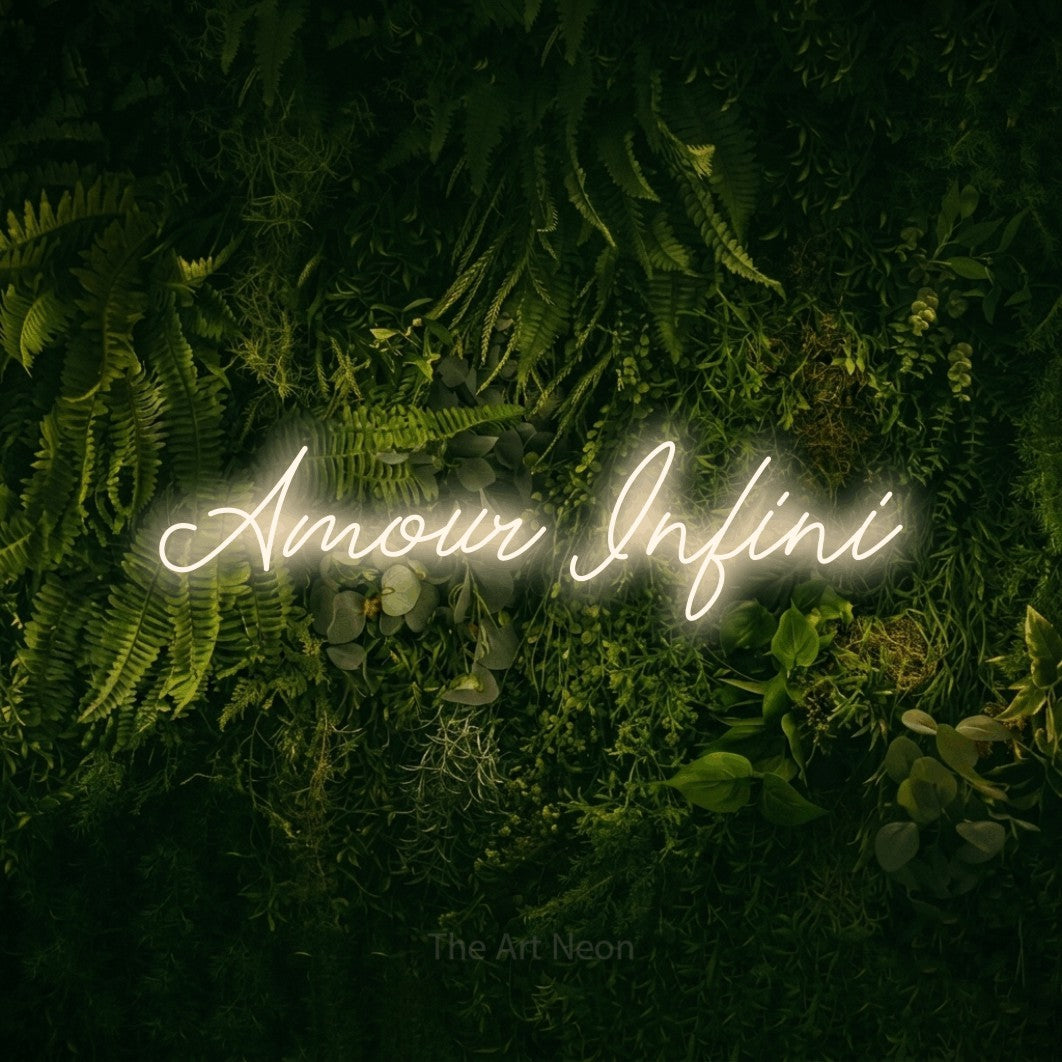 “Amour infini” LED neon sign in warm white, with cursive lettering, shown against a dark moss and forest backdrop.