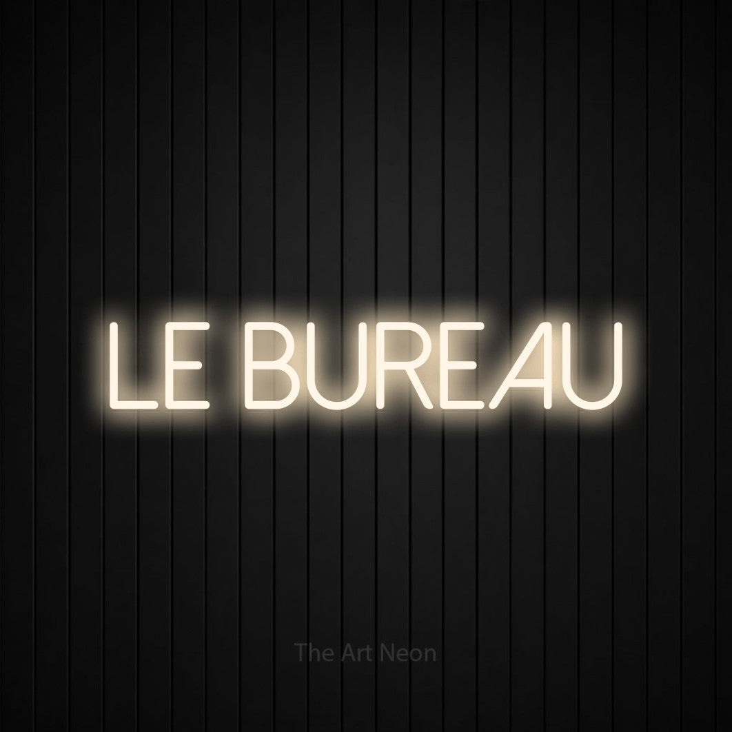 “Le bureau” LED neon sign in warm white, with thin sans-serif lettering, shown against black vertical wall slats.