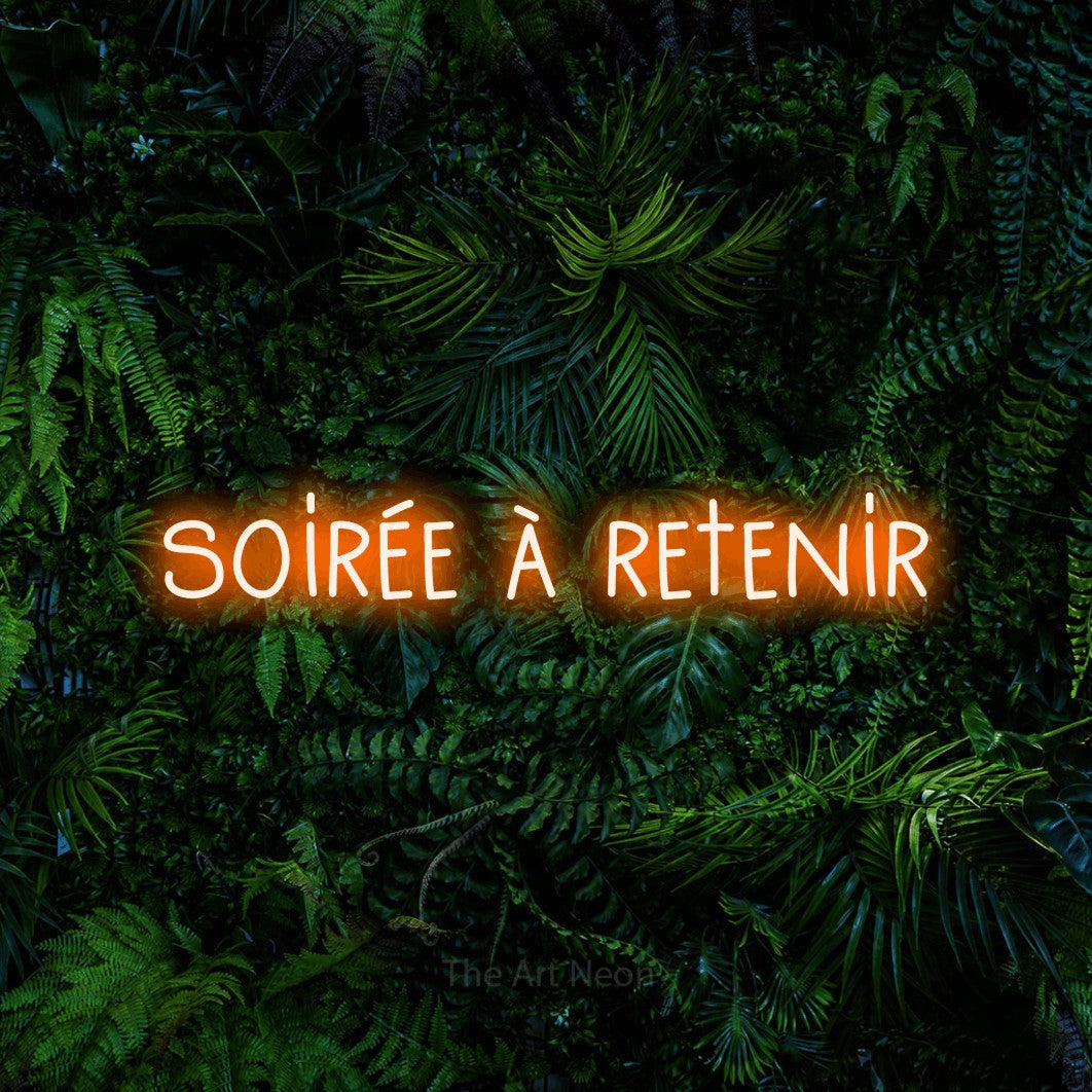 “Soirée à retenir” LED neon sign in orange, with narrow hand-drawn lettering, shown against dense tropical foliage.