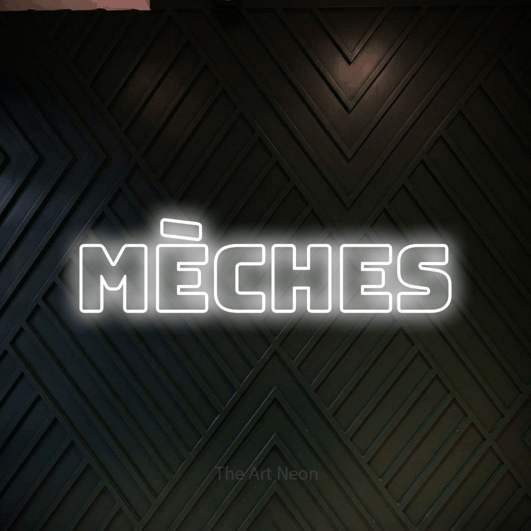 “Mèches” LED neon sign in cool white, with bold outline lettering, shown against a black chevron-patterned wood wall.