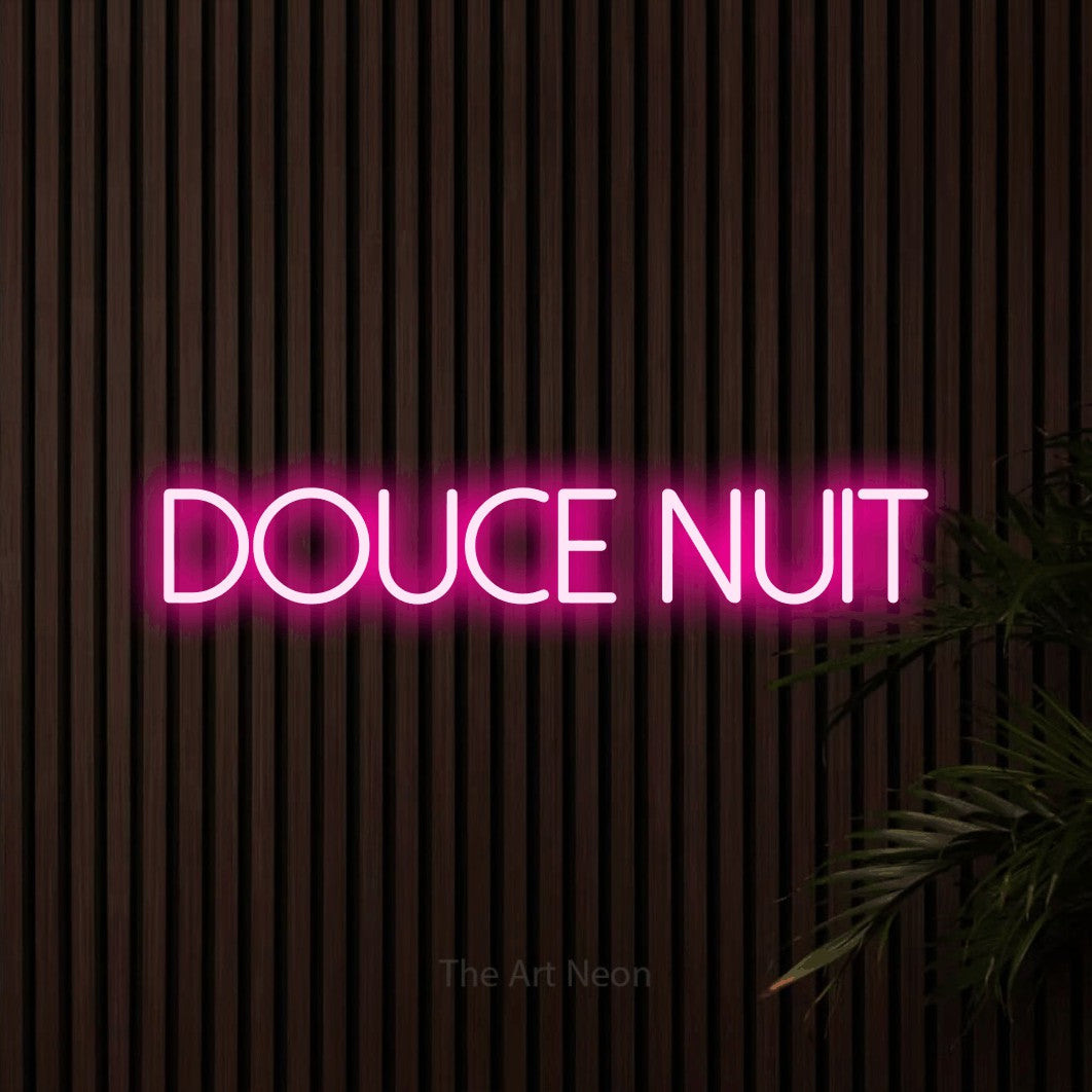 “Douce nuit” LED neon sign in hot pink, with thin sans-serif lettering, shown against dark wooden wall slats.