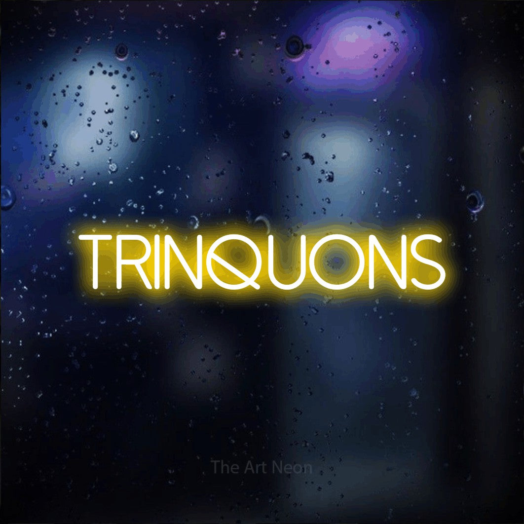 “Trinquons” LED neon sign in yellow, with thin sans-serif lettering, shown against glass with blue and purple reflections.