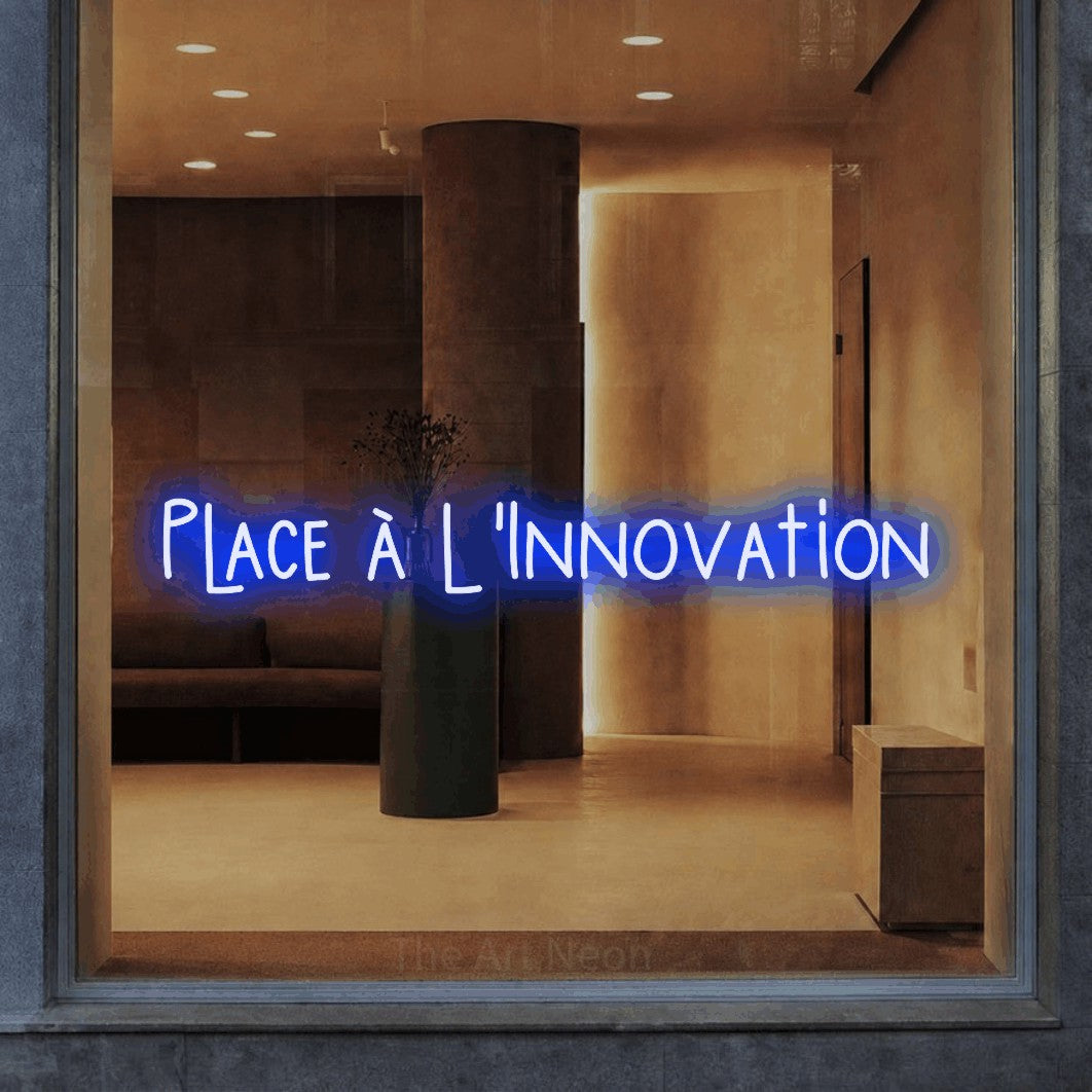 “Place à l'innovation” LED neon sign in blue, with narrow hand-drawn lettering, shown against a warm-toned interior.