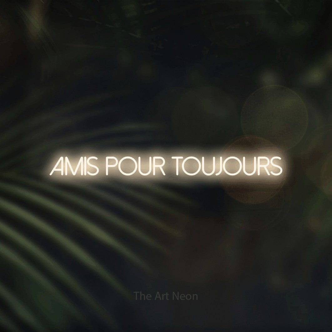 “Amis pour toujours” LED neon sign in warm white, with thin sans-serif lettering, shown against a blurred palm and bokeh-light backdrop.