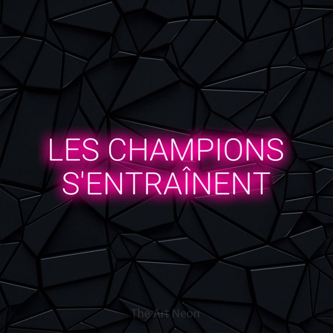 Aperçu d’une enseigne néon LED « Les champions s'entraînent » sur deux lignes en rose vif, en lettres sans empattement arrondies, photographiée sur une surface polygonale noire, pour un espace d’entraînement.