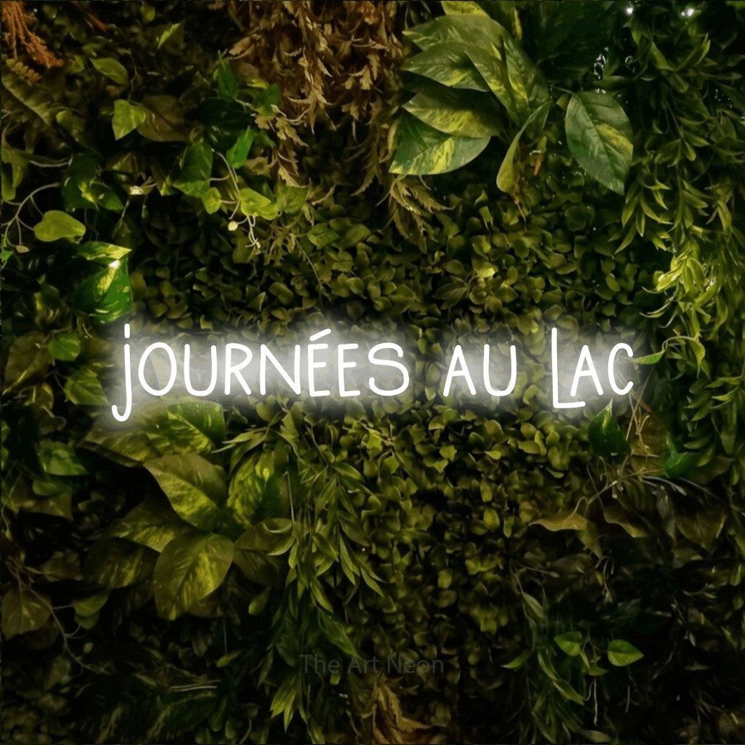 Enseigne néon LED « Journées au lac » en blanc froid, en lettres étroites dessinées à la main, présentée sur un feuillage vert et jaune vif, pour un décor inspiré de la nature.