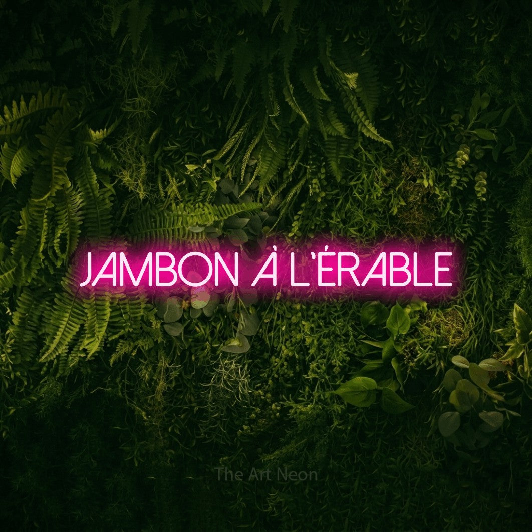 “Jambon à l'érable” LED neon sign in hot pink, with thin sans-serif lettering, shown against a dark moss and forest backdrop.