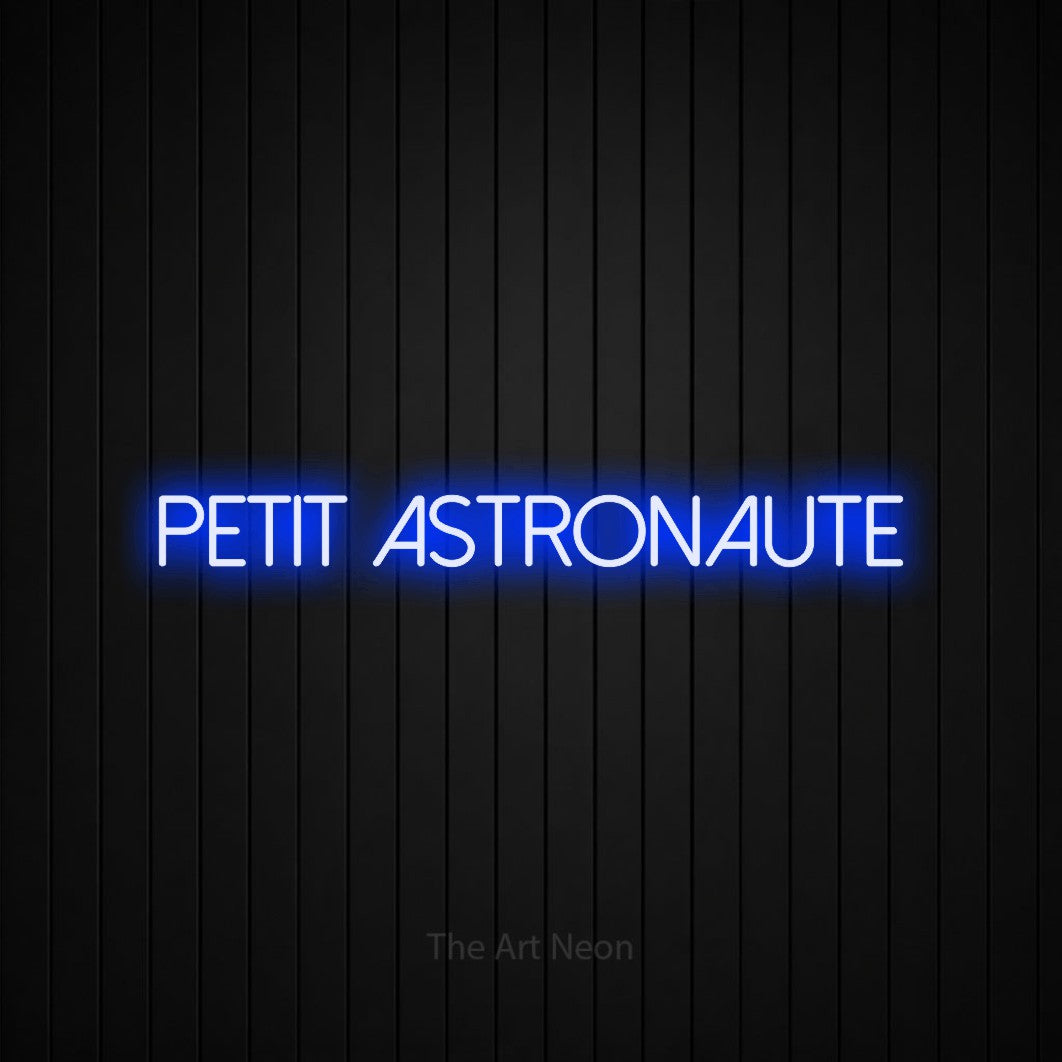 “Petit astronaute” LED neon sign in blue, with thin sans-serif lettering, shown against black vertical wall slats.