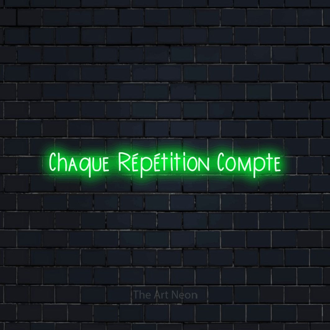 “Chaque répétition compte” LED neon sign in green, with narrow hand-drawn lettering, shown against a dark navy brick wall.