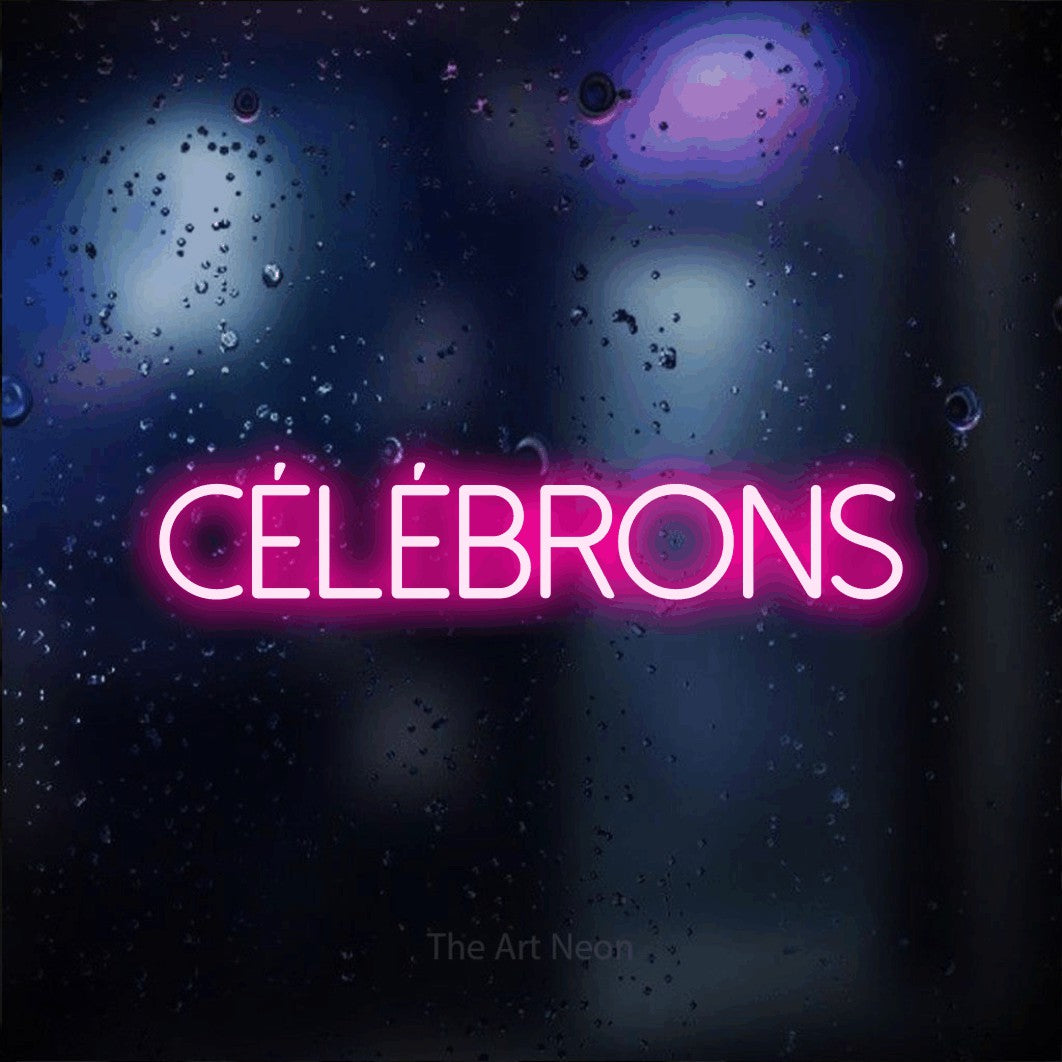 “Célébrons” LED neon sign in hot pink, with thin sans-serif lettering, shown against glass with blue and purple reflections.