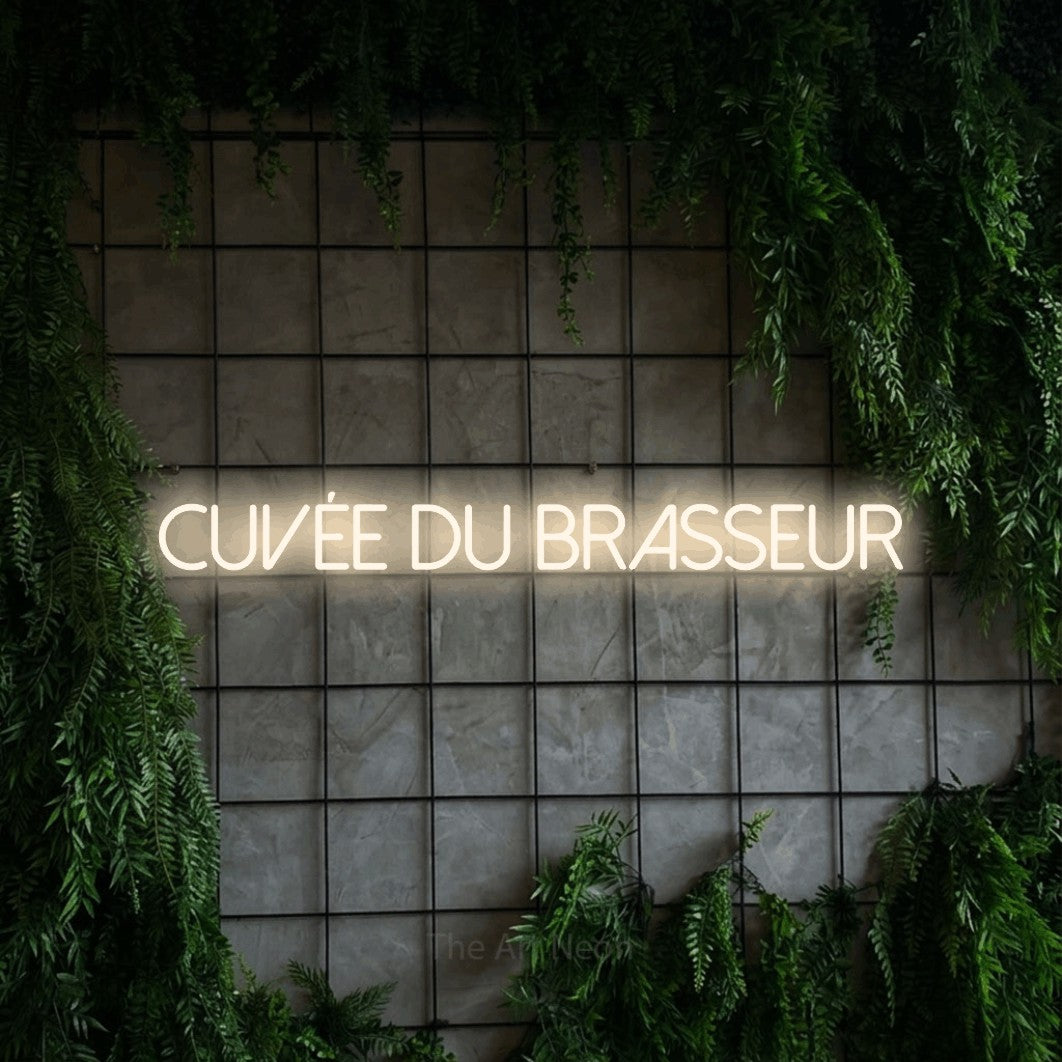 “Cuvée du brasseur” LED neon sign in warm white, with thin sans-serif lettering, shown against an ivy-covered concrete grid.