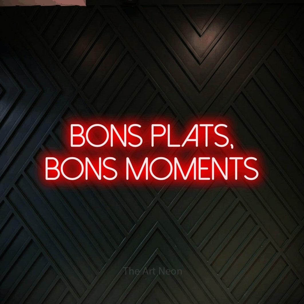 “Bons plats, bons moments” LED neon sign in red, with thin sans-serif lettering across 2 lines, shown against a black chevron-patterned wood wall.