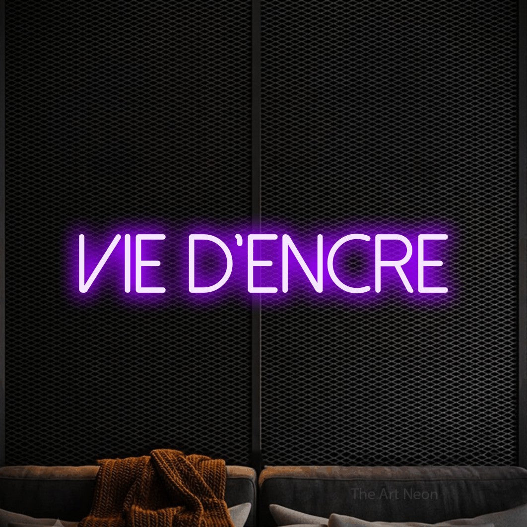 “Vie d'encre” LED neon sign in purple, with thin sans-serif lettering, shown against a modern dark-toned seating area.