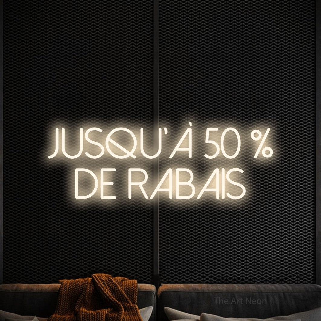 “Jusqu'à 50 % de rabais” LED neon sign in warm white, with thin sans-serif lettering across 2 lines, shown against a modern dark-toned seating area.