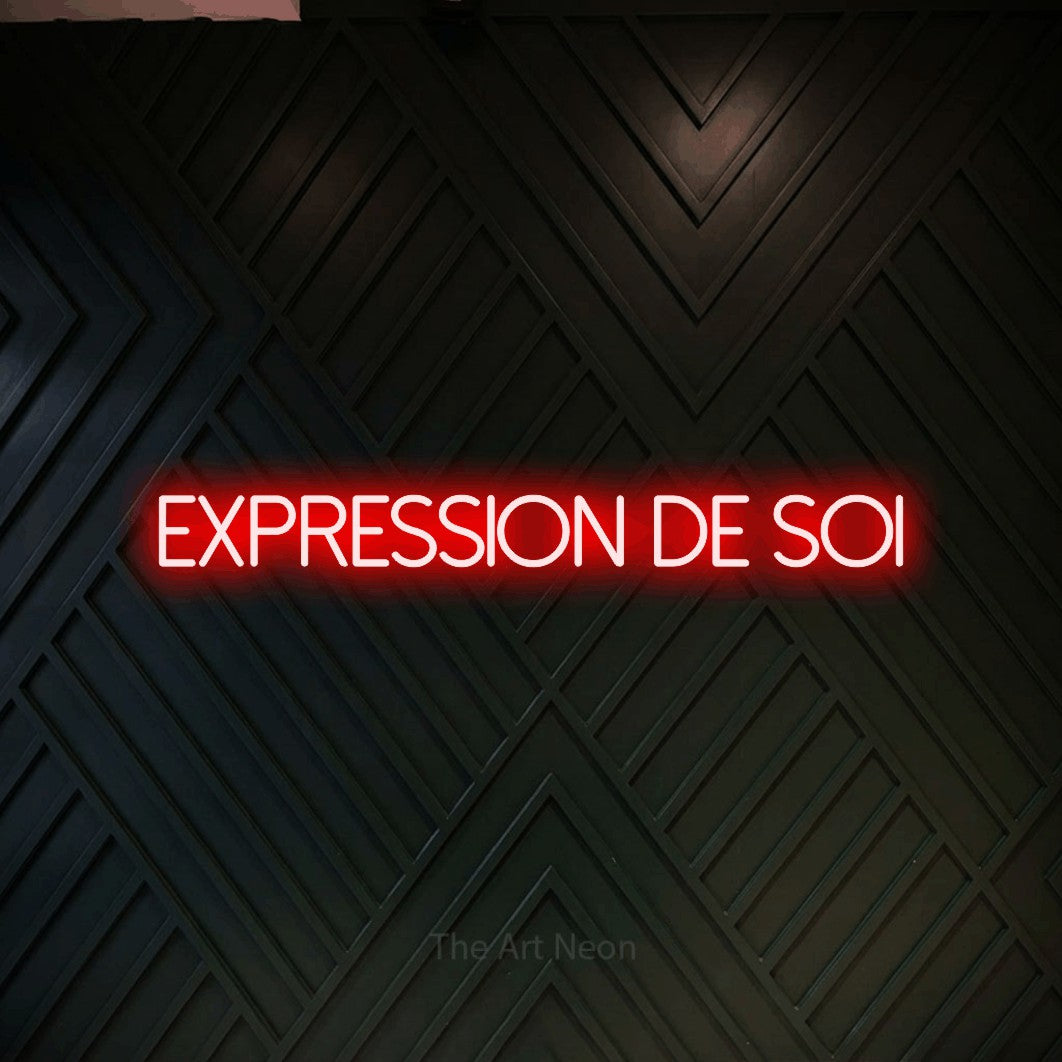 “Expression de soi” LED neon sign in red, with thin sans-serif lettering, shown against a black chevron-patterned wood wall.
