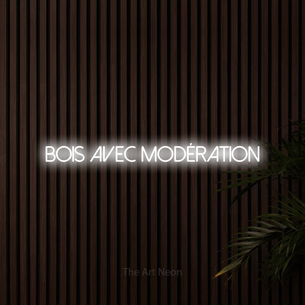 Composition en néon LED « Bois avec modération » en blanc froid, en lettres fines sans empattement, mise en valeur sur un mur de lattes en bois foncé, pour un bar à la maison.