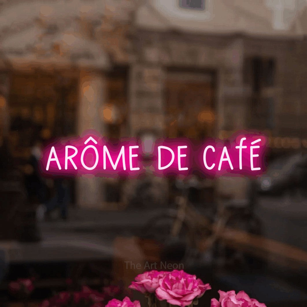 “Arôme de café” LED neon sign in hot pink, with narrow hand-drawn lettering, shown against a blurred café-bar interior.