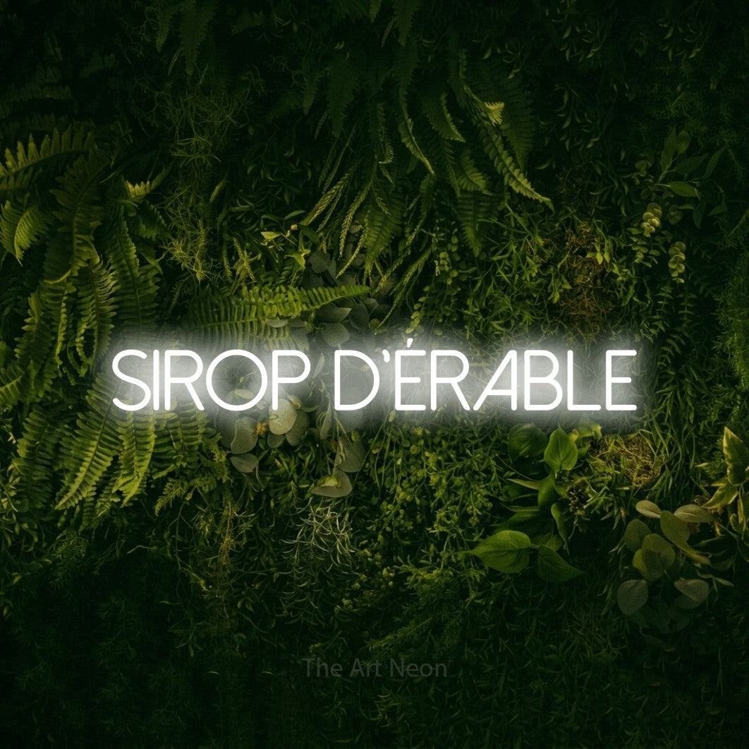“Sirop d'érable” LED neon sign in cool white, with thin sans-serif lettering, shown against a dark moss and forest backdrop.