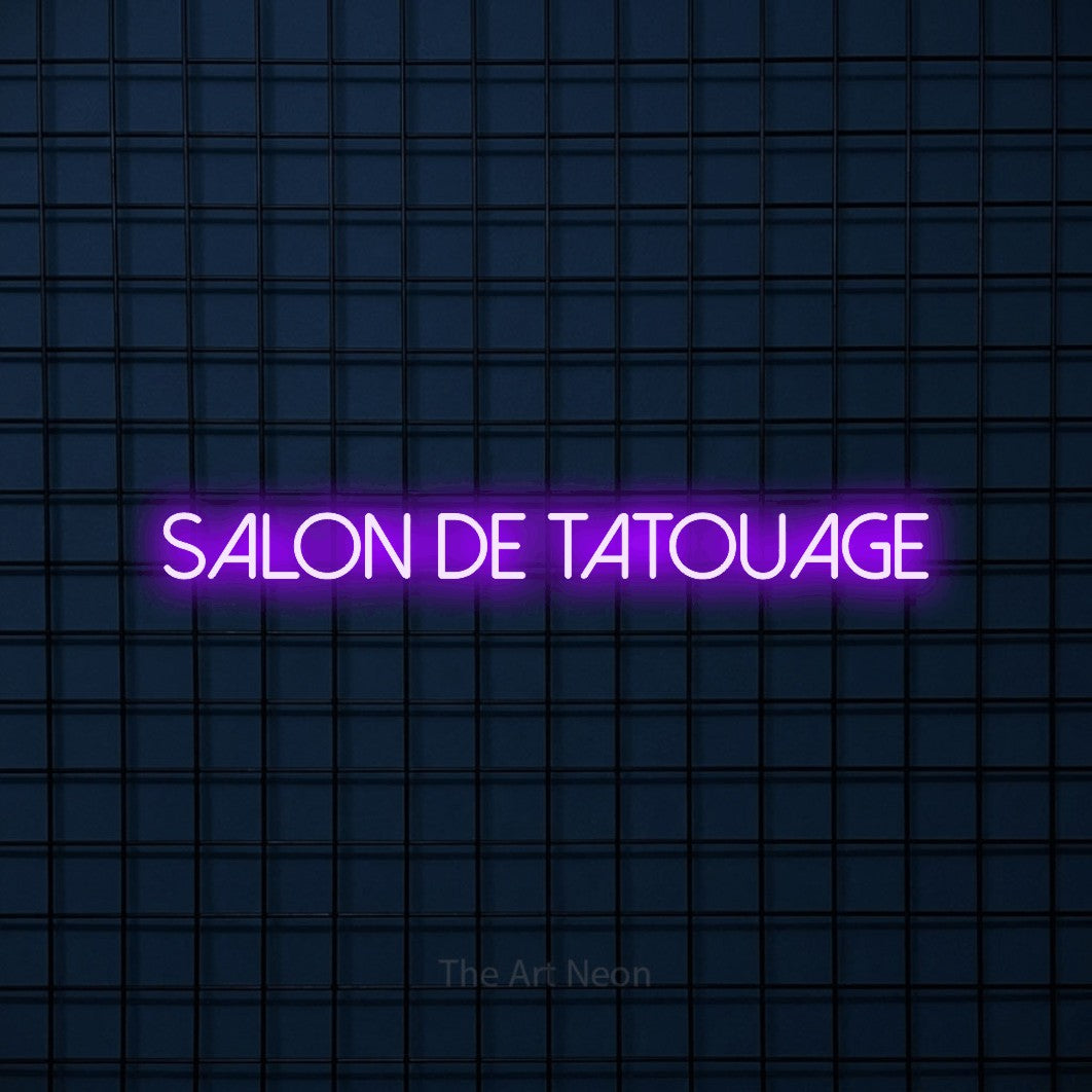 “Salon de tatouage” LED neon sign in purple, with thin sans-serif lettering, shown against a dark blue grid.