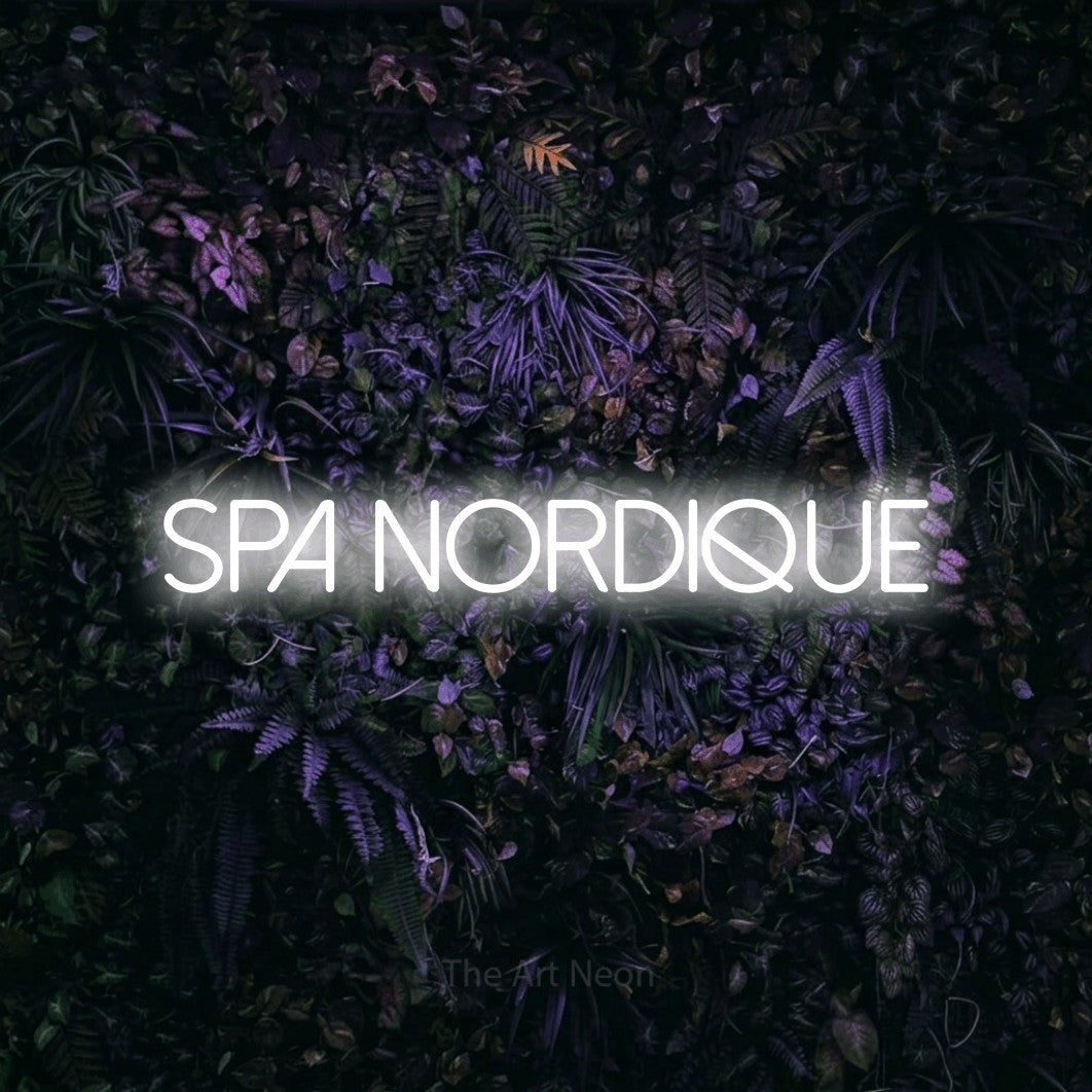 “Spa nordique” LED neon sign in cool white, with thin sans-serif lettering, shown against a dark wall with purple flowers.