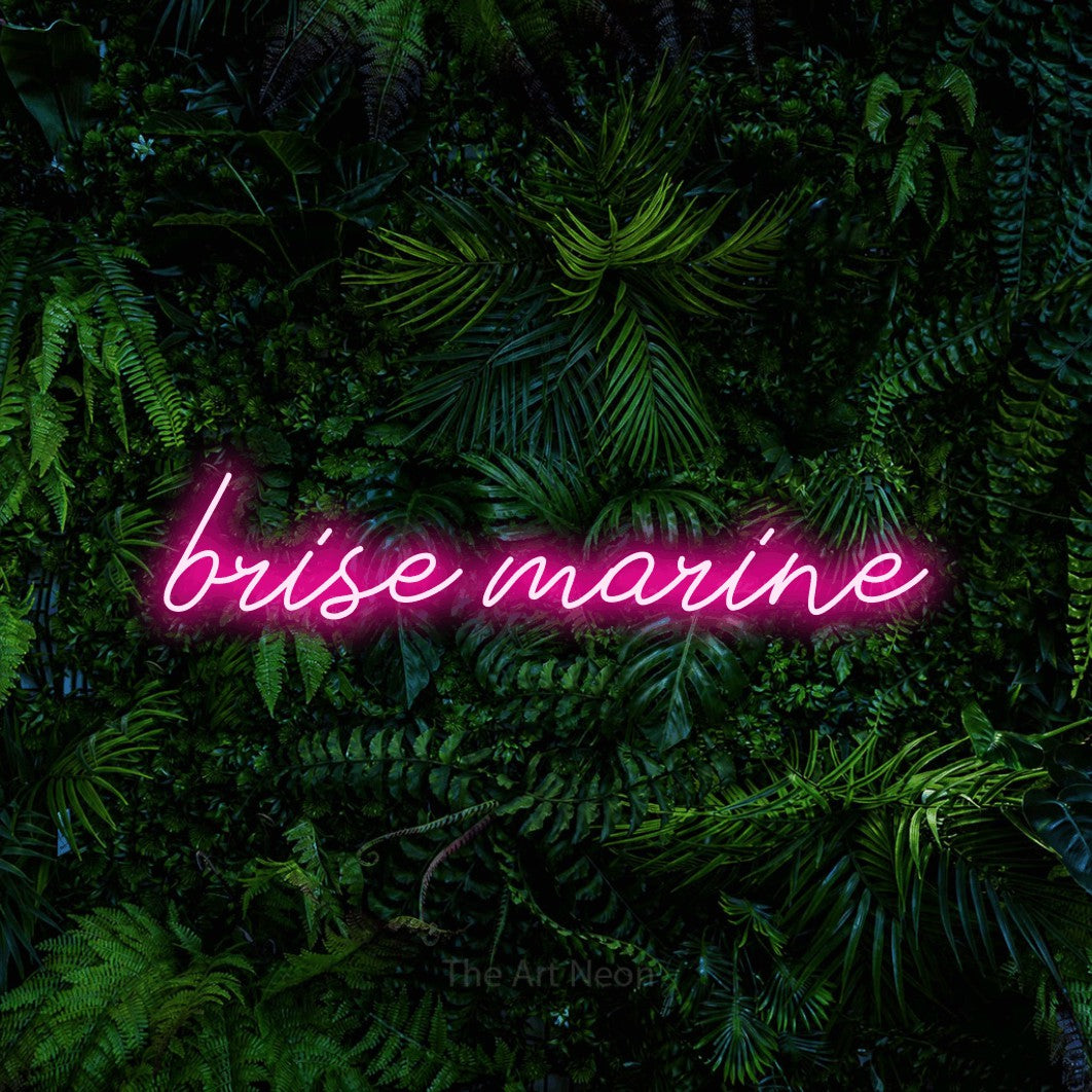 “Brise marine” LED neon sign in hot pink, with cursive lettering, shown against dense tropical foliage.
