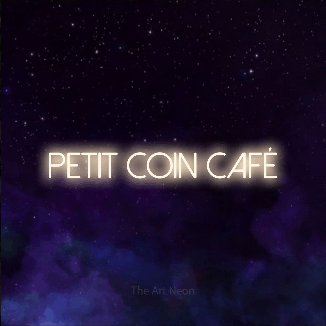 Aperçu d’une enseigne néon LED « Petit coin café » en blanc chaud, en lettres fines sans empattement, photographiée sur une texture de galaxie violette, pour un café.