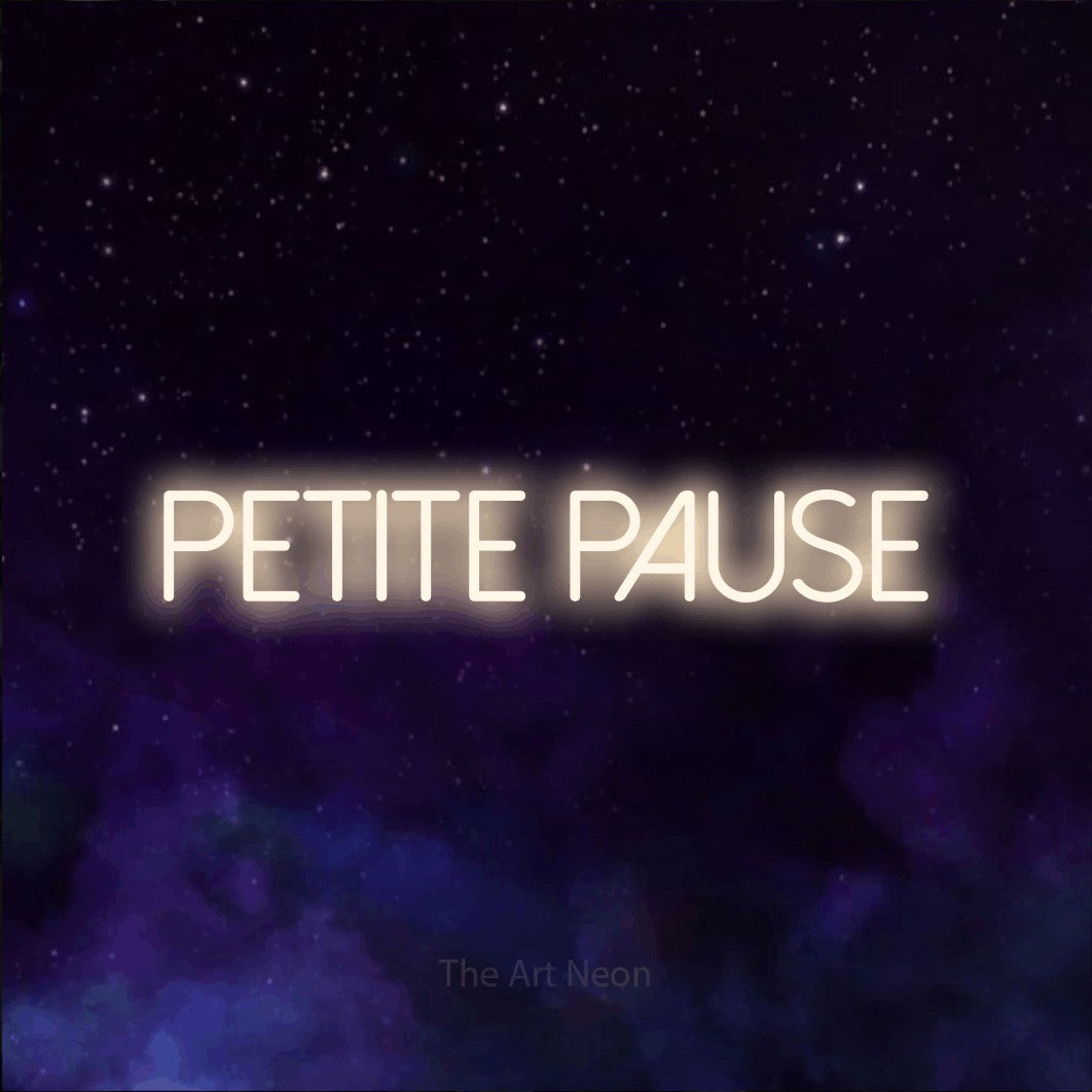 “Petite pause” LED neon sign in warm white, with thin sans-serif lettering, shown against a purple galaxy backdrop.