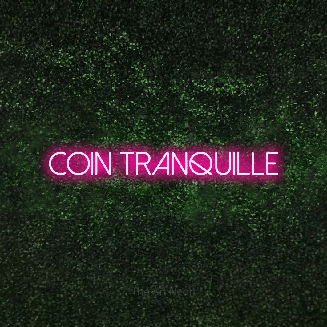 Enseigne néon LED « Coin tranquille » en rose vif, en lettres fines sans empattement, présentée sur une haie verte texturée, pour un café.