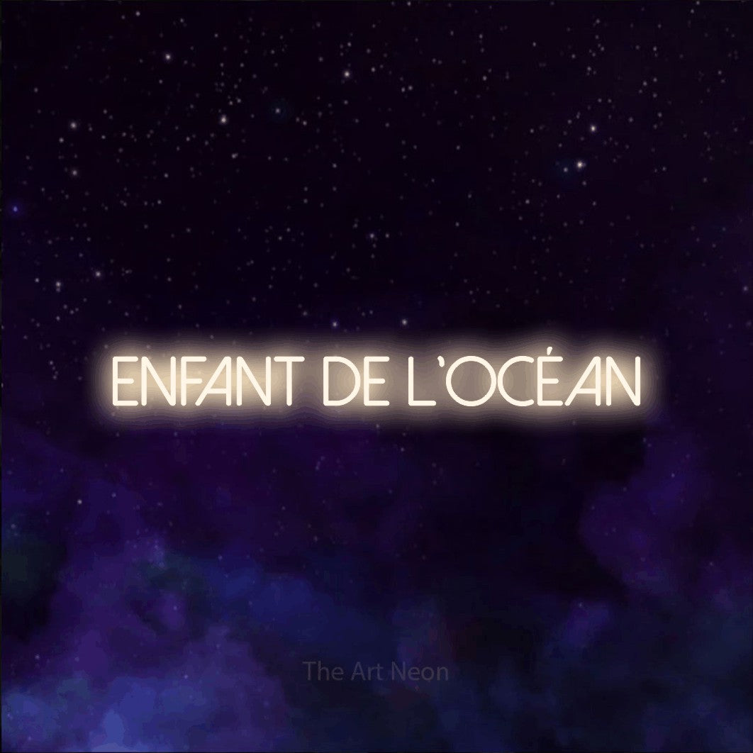 “Enfant de l'océan” LED neon sign in warm white, with thin sans-serif lettering, shown against a purple galaxy backdrop.