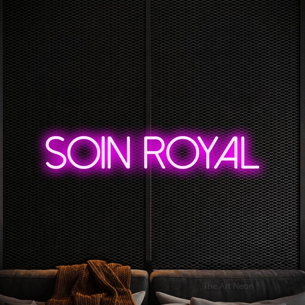 “Soin royal” LED neon sign in pink, with thin sans-serif lettering, shown against a modern dark-toned seating area.