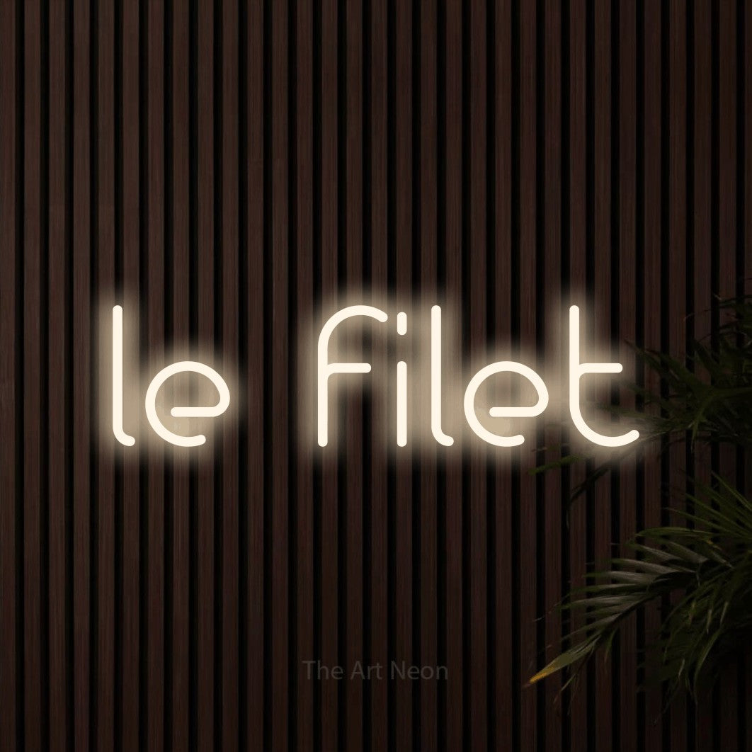 “Le filet” LED neon sign in warm white, with stylised geometric lettering, shown against dark wooden wall slats.