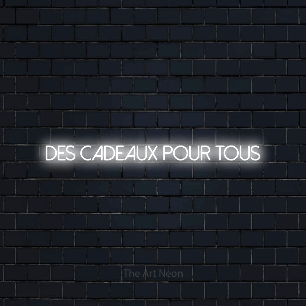 “Des cadeaux pour tous” LED neon sign in cool white, with thin sans-serif lettering, shown against a dark navy brick wall.