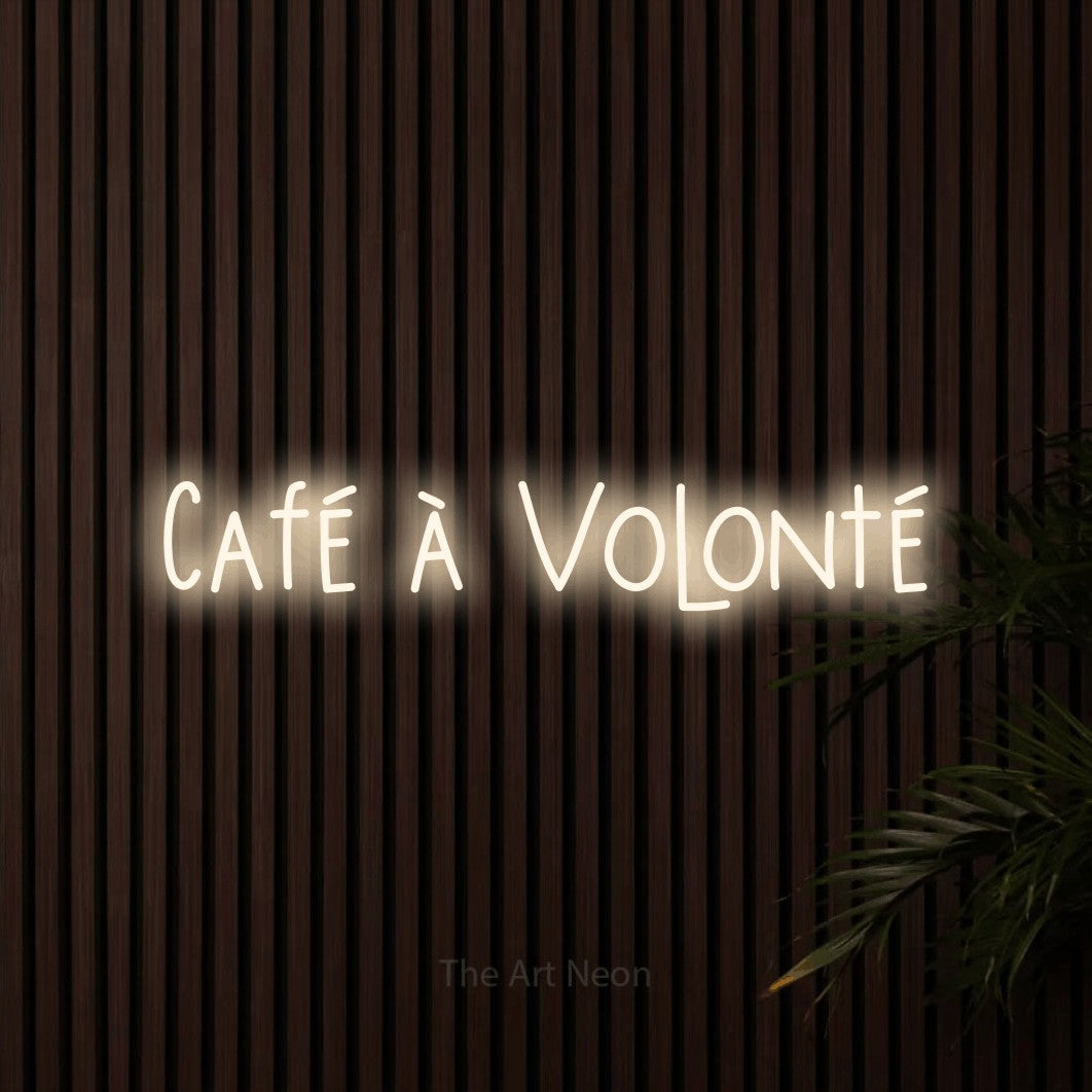 “Café à volonté” LED neon sign in warm white, with narrow hand-drawn lettering, shown against dark wooden wall slats.