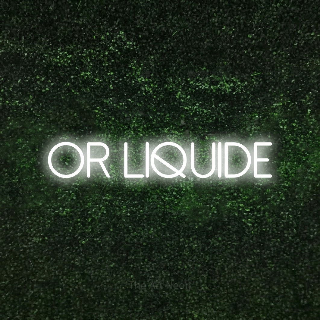 “Or liquide” LED neon sign in cool white, with thin sans-serif lettering, shown against a textured green hedge.