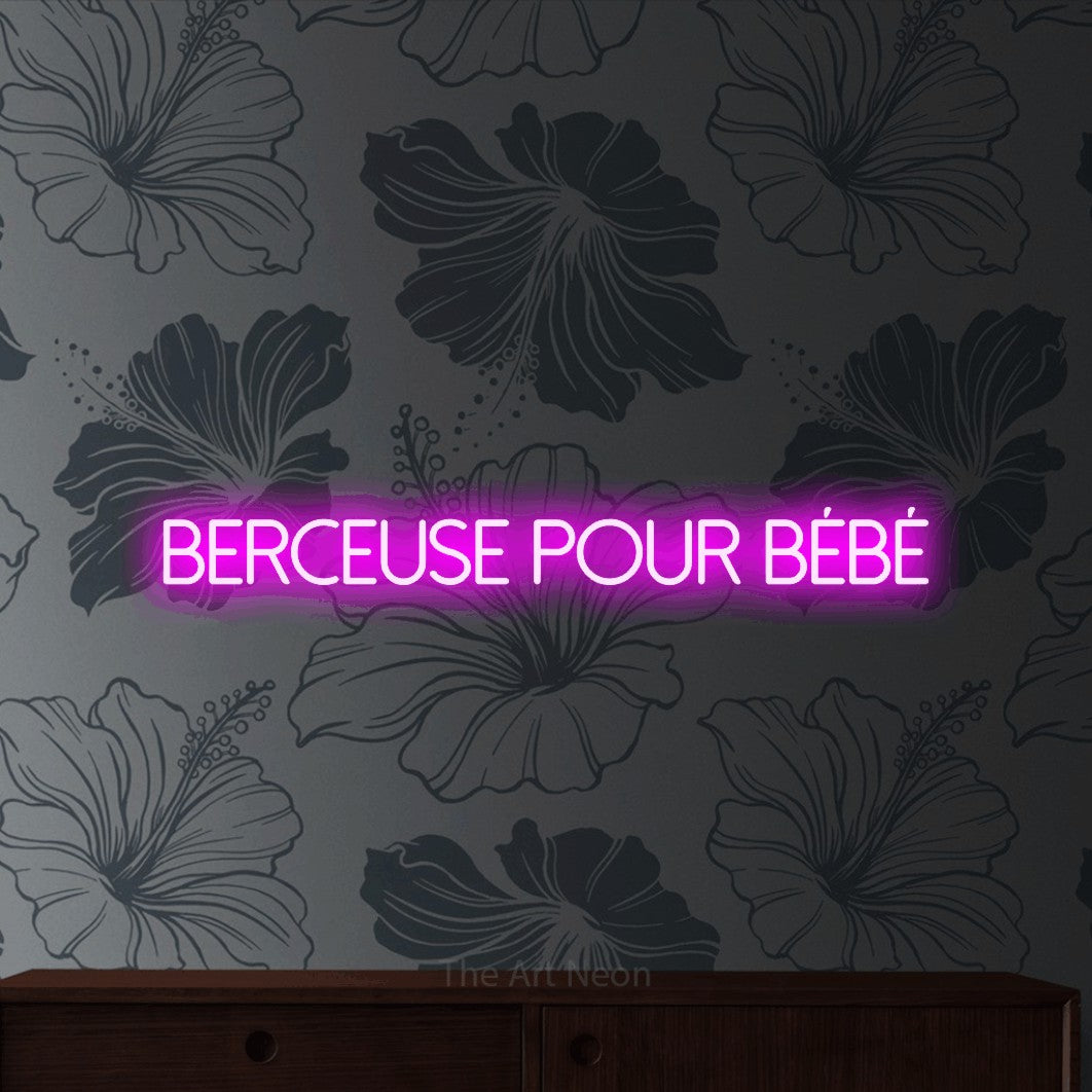 Néon LED « Berceuse pour bébé » en rose, en lettres fines sans empattement, mis en scène sur un mur gris à motifs floraux, pour une fête prénatale.