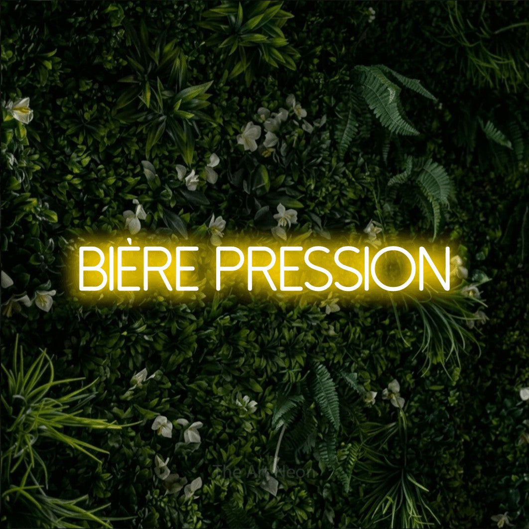 “Bière pression” LED neon sign in yellow, with thin sans-serif lettering, shown against a dense green plant wall.