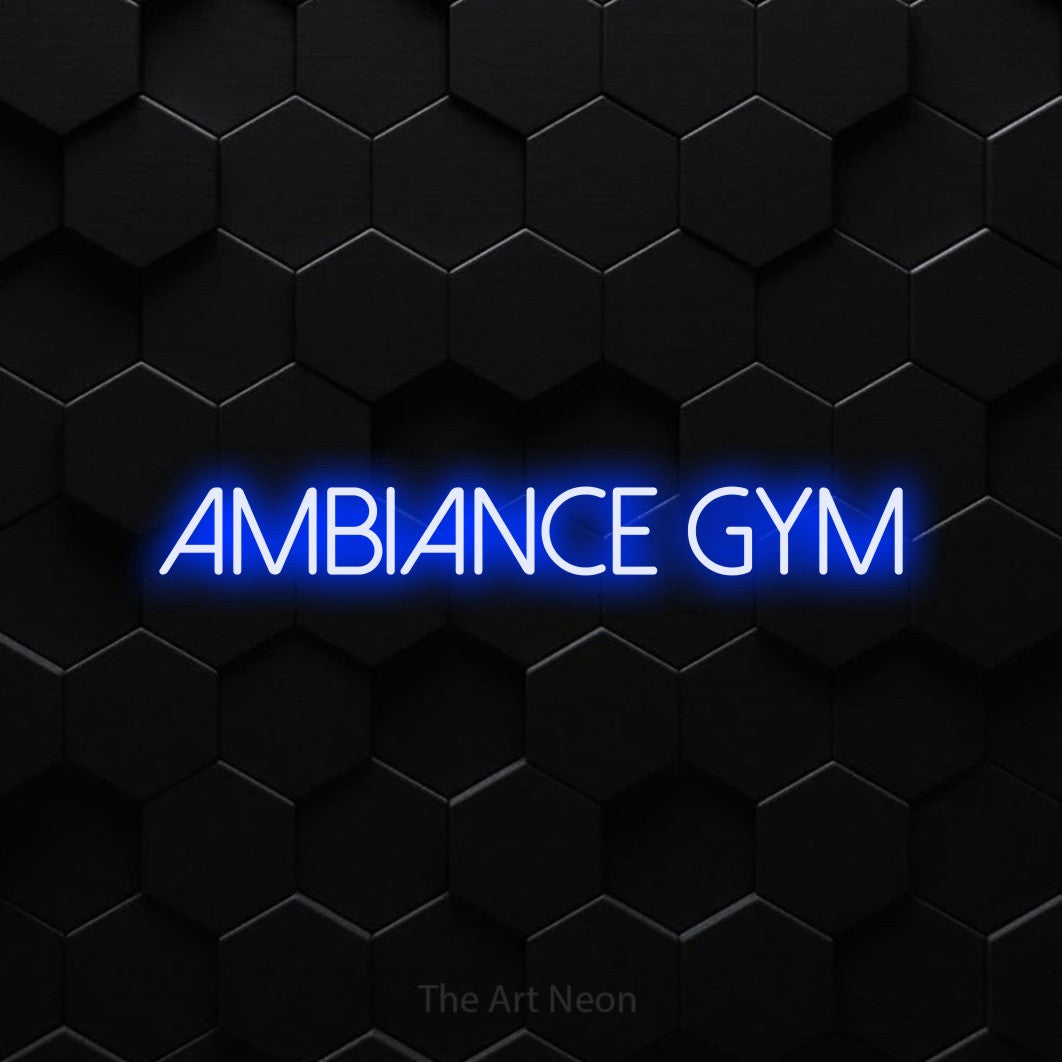 Néon LED « Ambiance gym » en bleu, en lettres fines sans empattement, mis en scène sur un mur de carreaux hexagonaux noirs, pour un espace d’entraînement.