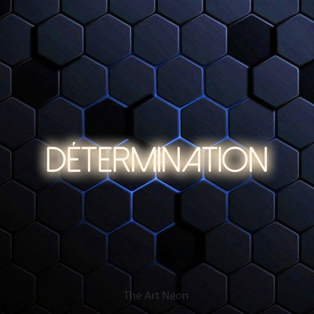 “Détermination” LED neon sign in warm white, with thin sans-serif lettering, shown against a dark blue honeycomb pattern.