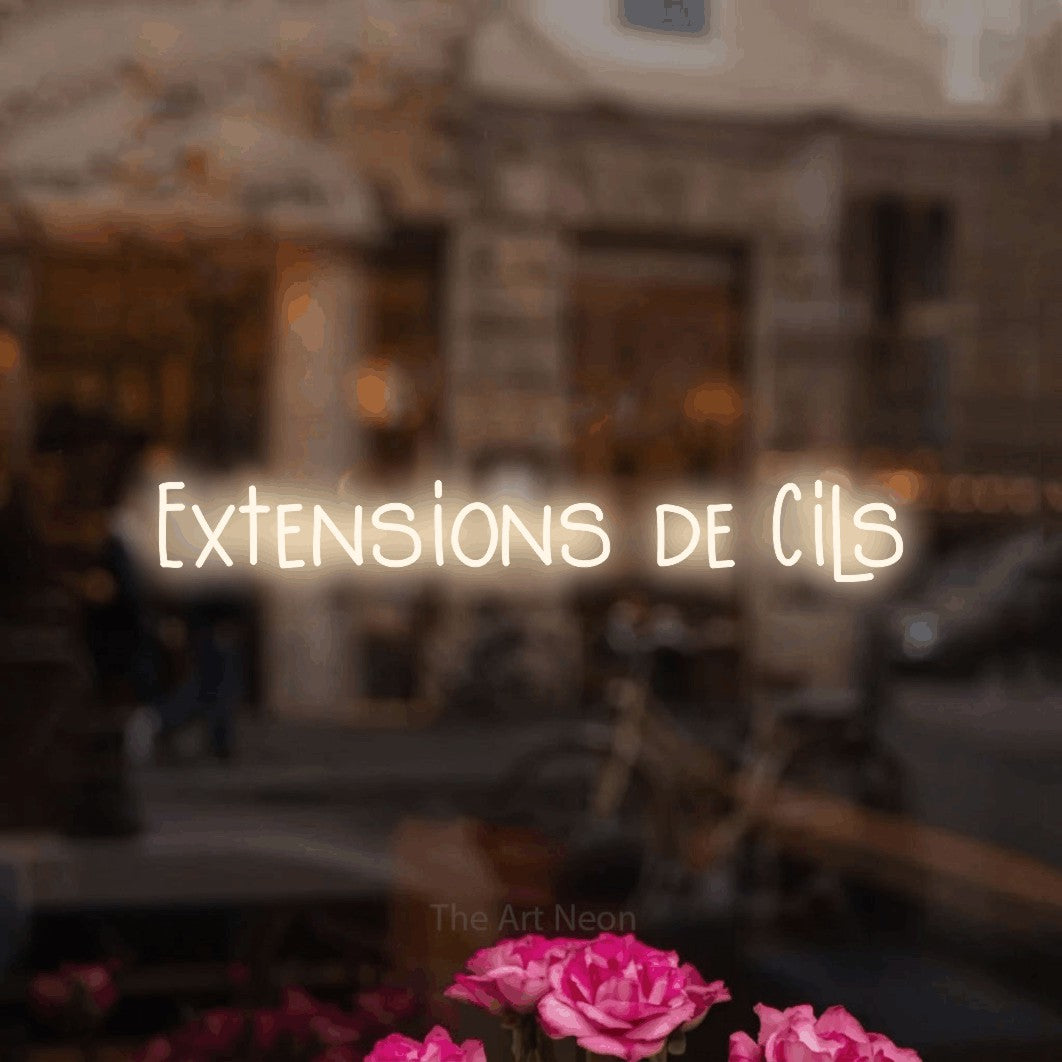 “Extensions de cils” LED neon sign in warm white, with narrow hand-drawn lettering, shown against a blurred café-bar interior.