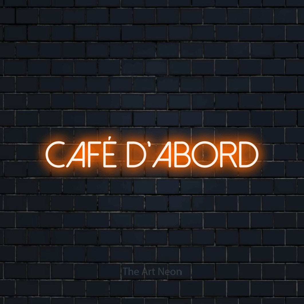 Enseigne néon LED « Café d'abord » en orange, en lettres fines sans empattement, présentée sur un mur de briques bleu marine foncé, pour une cuisine.