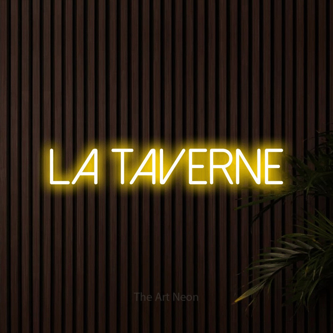 “La taverne” LED neon sign in yellow, with thin sans-serif lettering, shown against dark wooden wall slats.