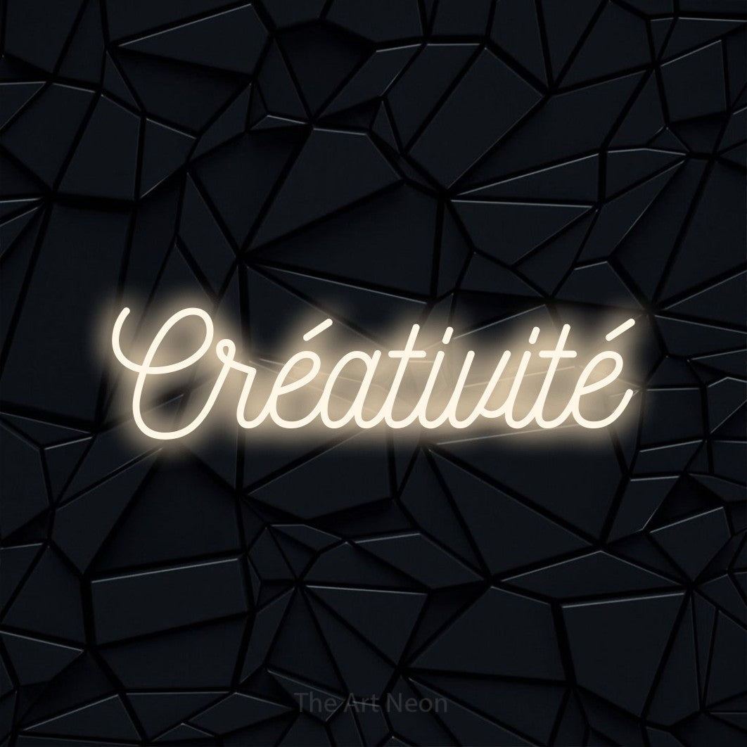 “Créativité” LED neon sign in warm white, with ornate cursive lettering, shown against a black polygonal surface.