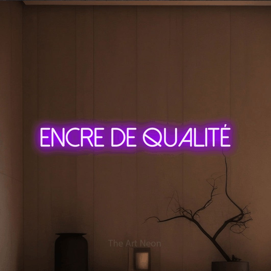 “Encre de qualité” LED neon sign in purple, with thin sans-serif lettering, shown against a simple earth-toned interior.
