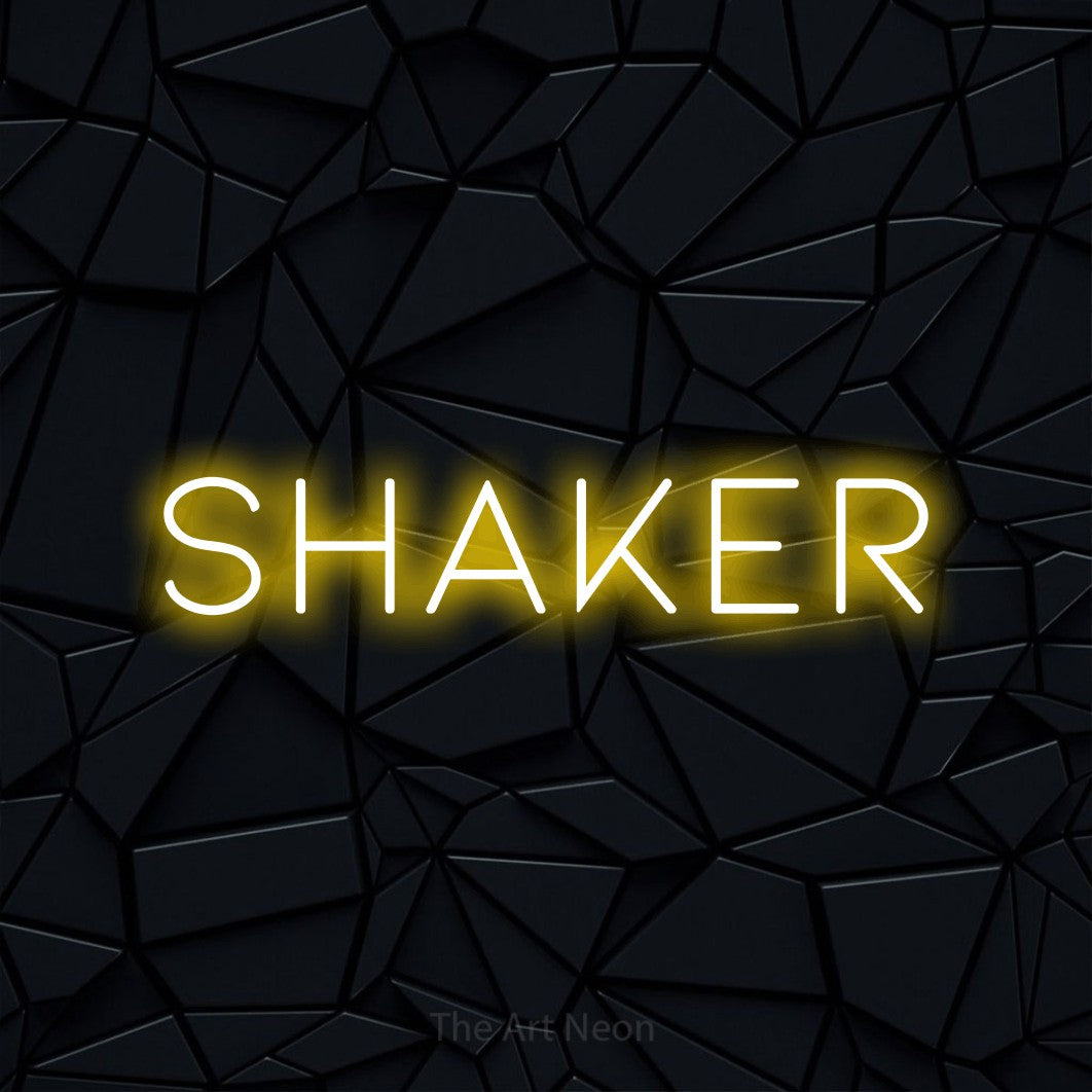 “Shaker” LED neon sign in yellow, with thin, widely spaced lettering, shown against a black polygonal surface.
