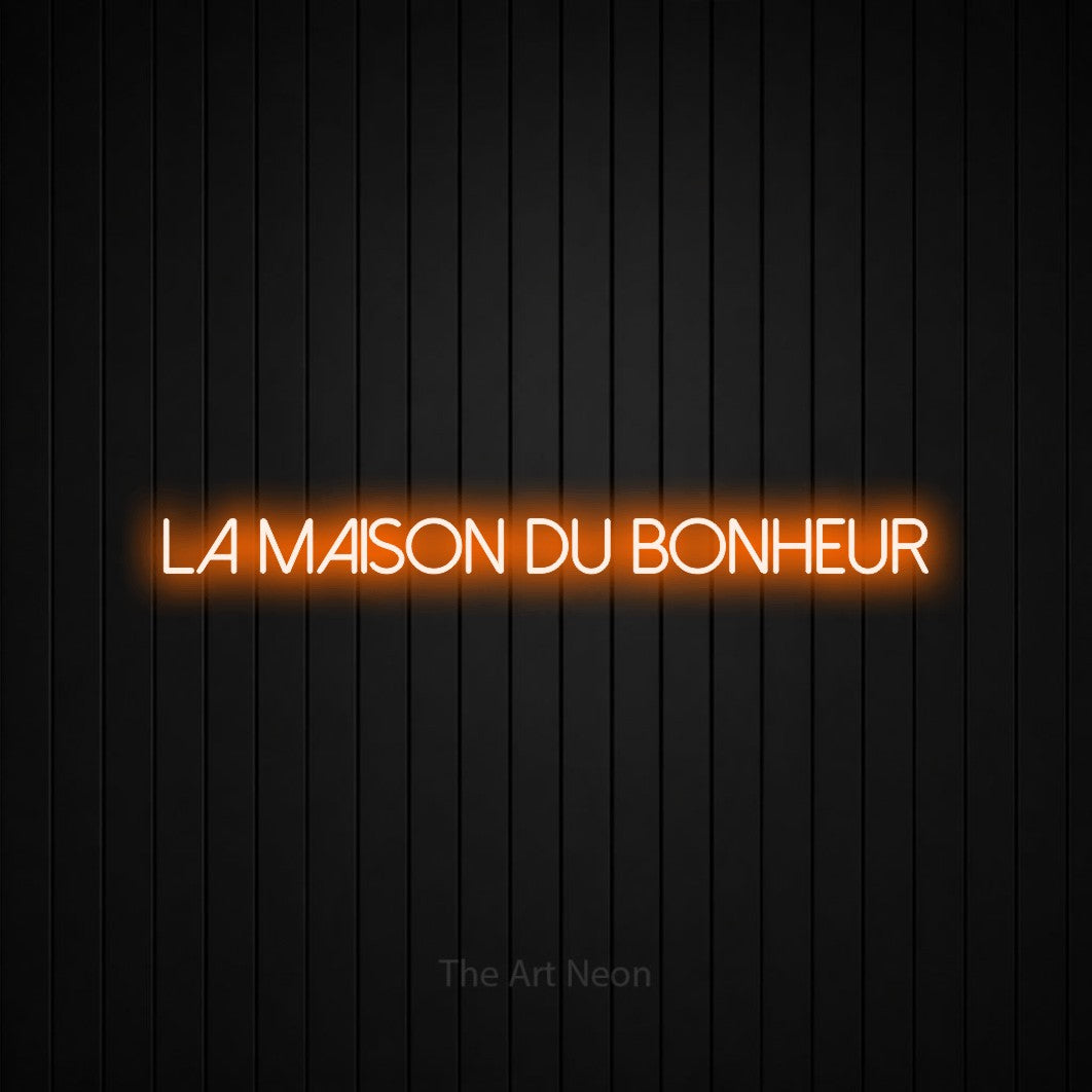 “La maison du bonheur” LED neon sign in orange, with thin sans-serif lettering, shown against black vertical wall slats.